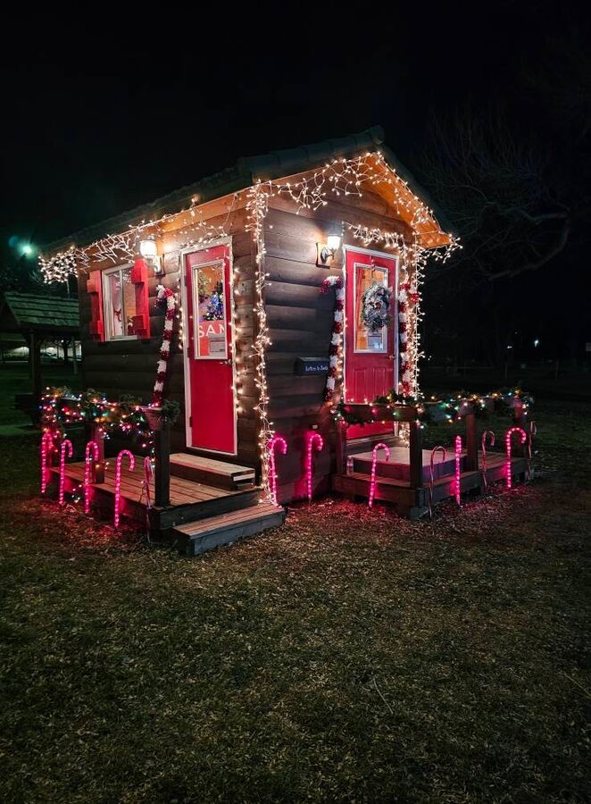 Santa's cabin glowing with Christmas lights and candy canes at night